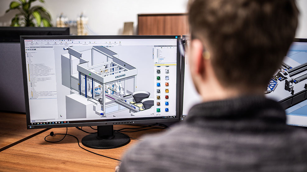 Ein Konstrukteur sitz vor dem Computer und plant an einem 3D-Modell einer Anlage.