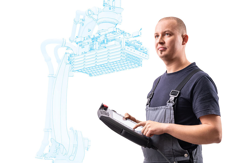 Ein Techniker bedient mit einer Steuereinheit einen virtuell gezeichneten Roboterarm.